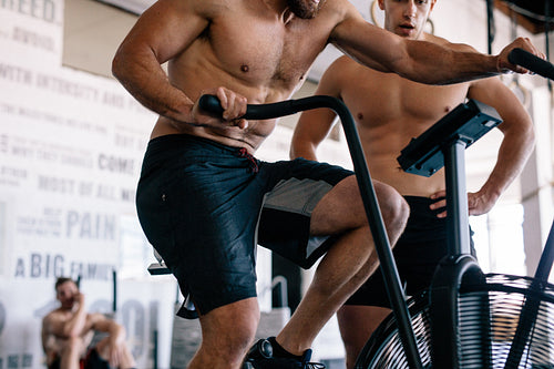 Personal trainer assisting athlete on gym bike