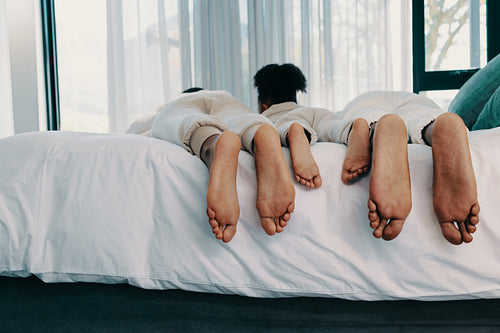 Weekend family moment, parents lying on a bed with their daughter