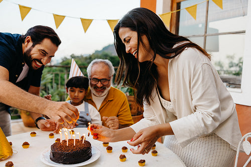 Family celebrating a birthday outdoors with cake and decorations