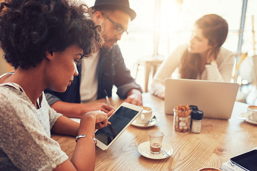 Young african woman using digital tablet with friends at cafe
