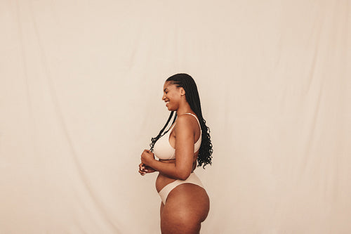 Smiling young woman wearing beige underwear in a studio