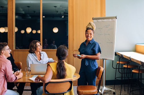 Smiling presenter leading a group discussion in a well-lit conference room
