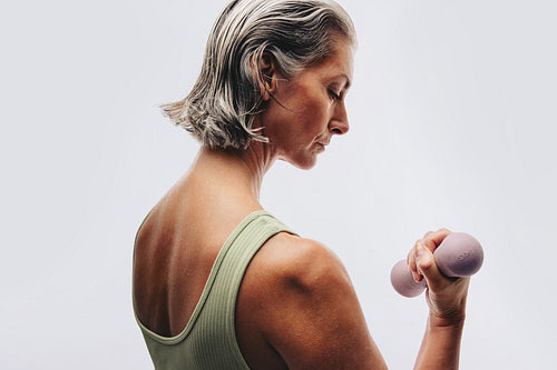 Older woman lifting dumbbell in studio workout