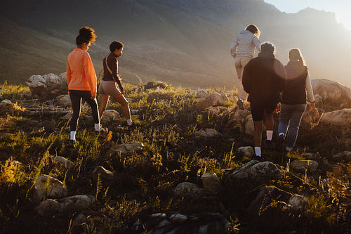 Group hiking together uphill at sunset