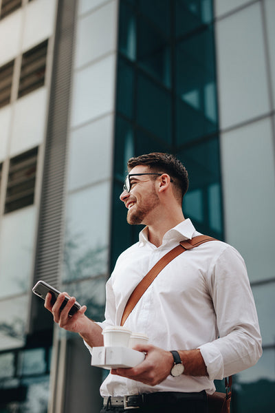 Businessman going to office holding mobile phone and coffee