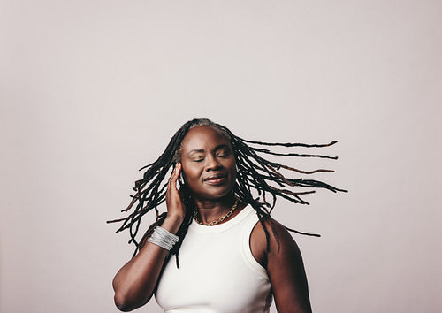 Black woman with dreadlocks listening to vibrant music on earbuds