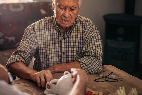 Senior men being served tea by a friend
