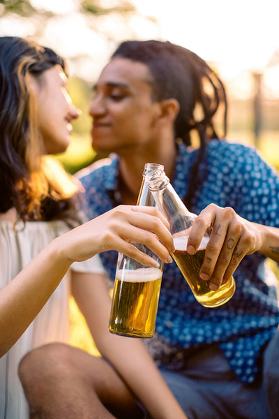 Affectionate young couple toasting beer bottles