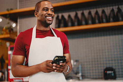 Small business owner holding a contactless payment machine in a cafe