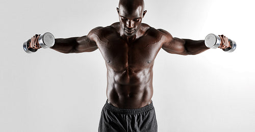 Shirtless muscular man exercising with hand weights