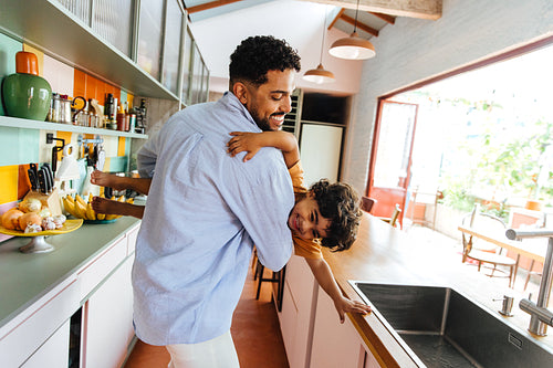 Father and son playing together in a modern kitchen setting