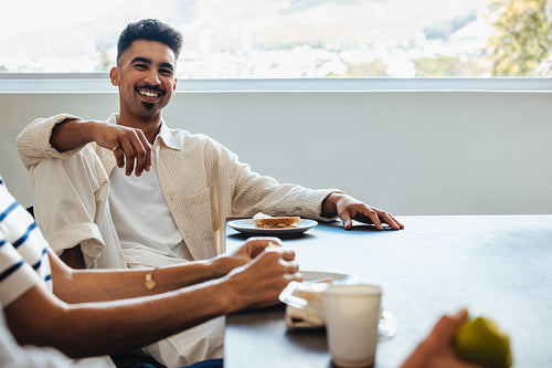 Young professional enjoying coffee break with colleagues in a modern office setting