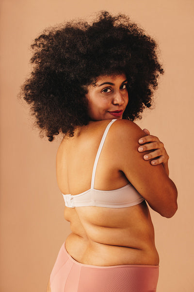 Body confident plus size woman embracing herself in a studio