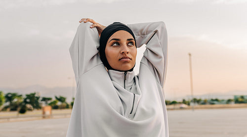 Muslim woman doing stretch exercises outdoors