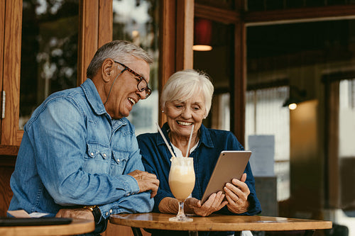 Senior couple at cafe using digital tablet
