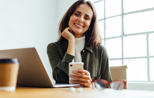 Portrait of a happy business woman using a mobile phone at work