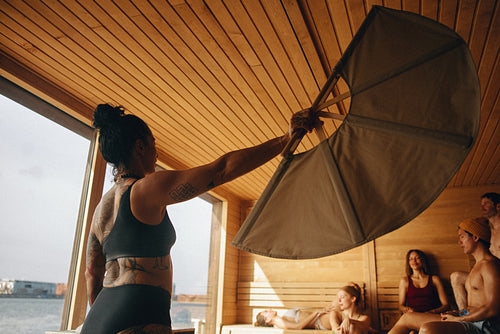 The sauna becomes a calm spa setting with a sauna master fanning heat for the group.