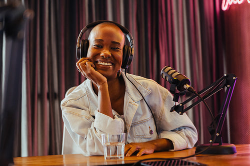 Radiant podcast host smiling in studio with professional microphone and headphones