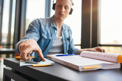Student at college library with books and mobile phone