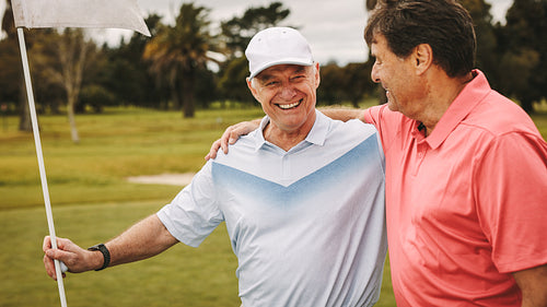 Two smiling senior golf players on the green