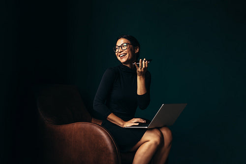 Businesswoman with laptop talking on mobile phone