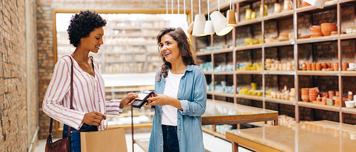 Happy shop owner receiving a contactless credit card payment from a customer
