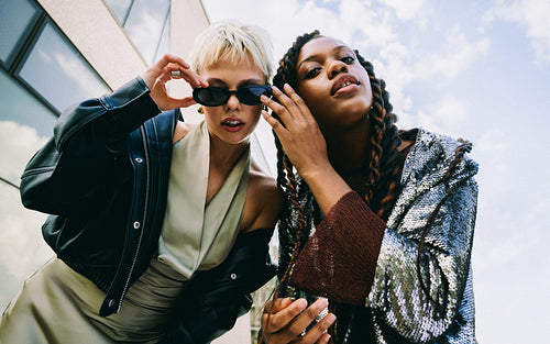 Friends and women adjust sunglasses on a city street