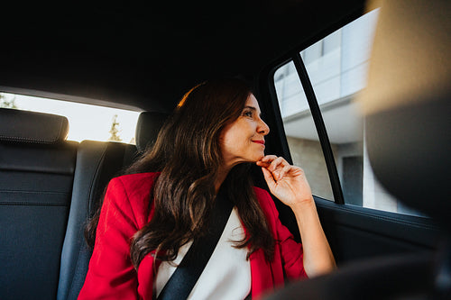 Businesswoman in a car looking outside wearing professional attire