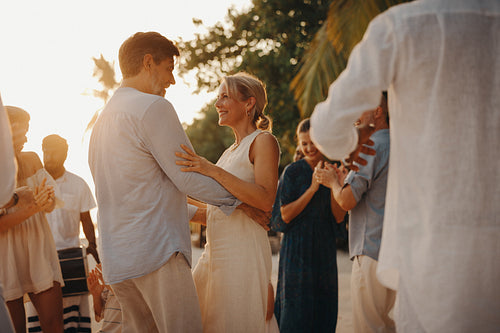 Mature couple dancing on island vacation with family and friends