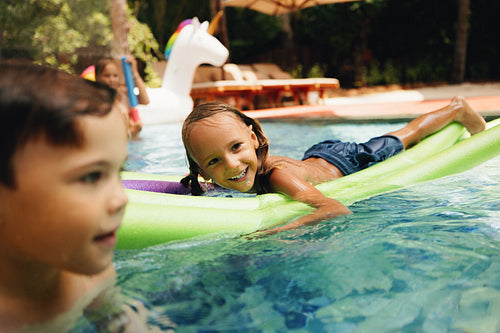 Joyful children swimming in the pool during summer, having fun and smiling