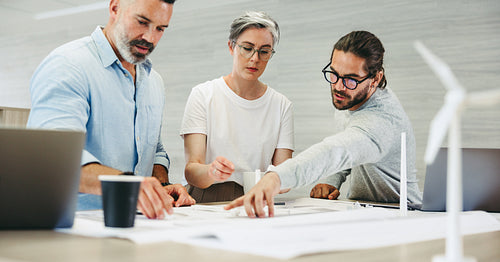 Group of creative designers working with wind turbine blueprints