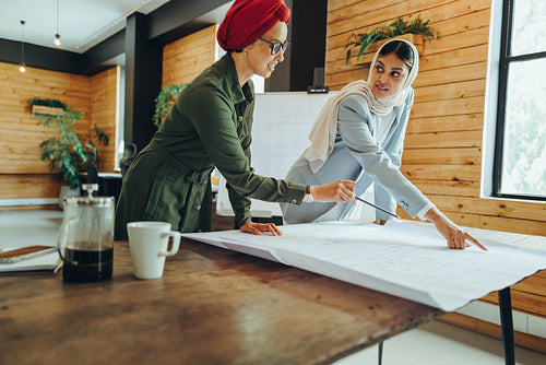 Innovative Muslim designers working with blueprints in an office