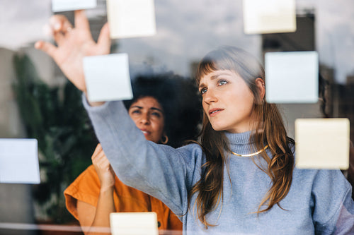 Businesswomen brainstorming using adhesive notes