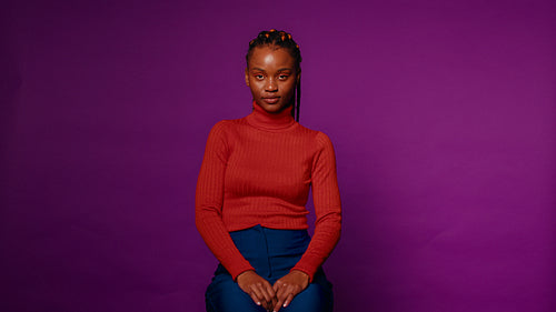 Portrait of a serene young woman against a vibrant violet backdrop