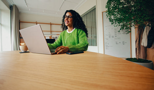 In a bright office, business work unfolds as a woman types at her laptop desk
