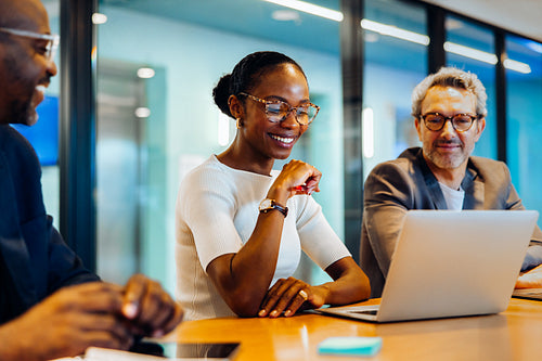 Group of professionals brainstorming around a laptop at a business meeting