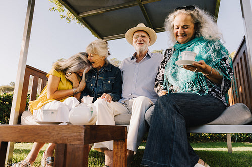 Group of senior friends laughing together over tea