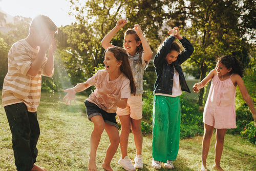 Group of young friends having fun playing outdoors in the sunshine