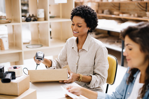 Smiling online store owner scanning the barcode of a package box