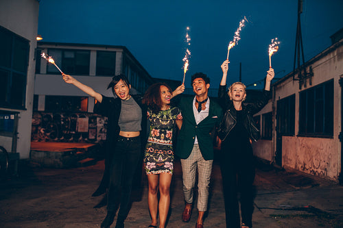 Friends enjoying nighttime party with sparklers in city