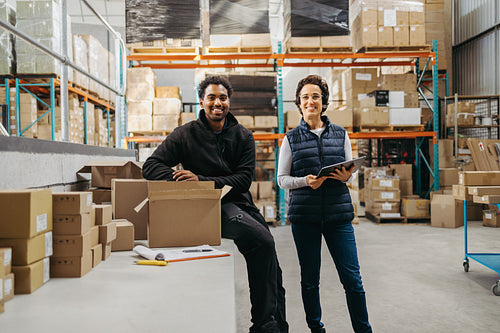 Happy warehouse employees smiling at the camera in a logistics centre