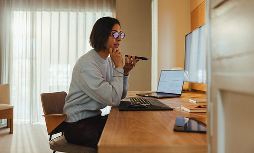 Focused woman speaks on the phone while working at her desk in a home office