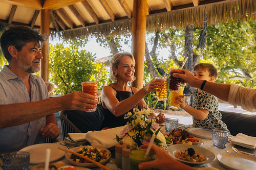 Family enjoying breakfast together on a luxury vacation and toasting with colorful drinks
