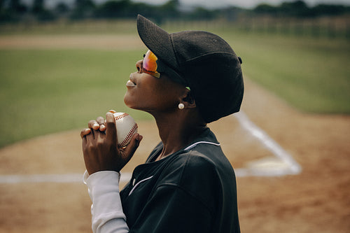 Baseball pitcher wearing sunglasses and a hat gazes upwards thoughtfully