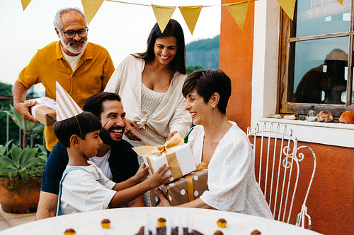 Family celebrating birthday outdoors with presents and decorations