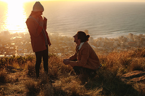 Man kneeling to female on cliff