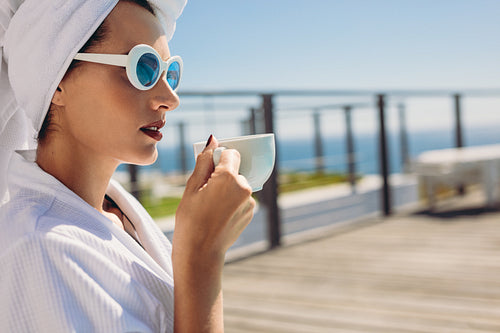 Woman sitting by pool having coffee
