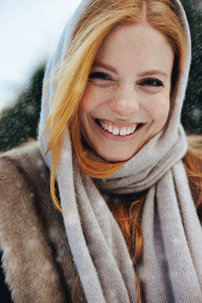 Smiling redhead woman enjoys snow outdoors in winter