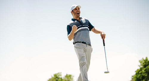 Happy male golfer shouts in victory celebrating a successful putt