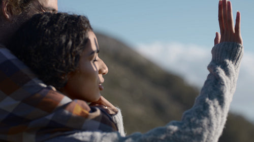 Woman with boyfriend looking at the sun through her fingers